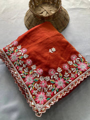 Red embroidered fabric with floral patterns on a light gray background