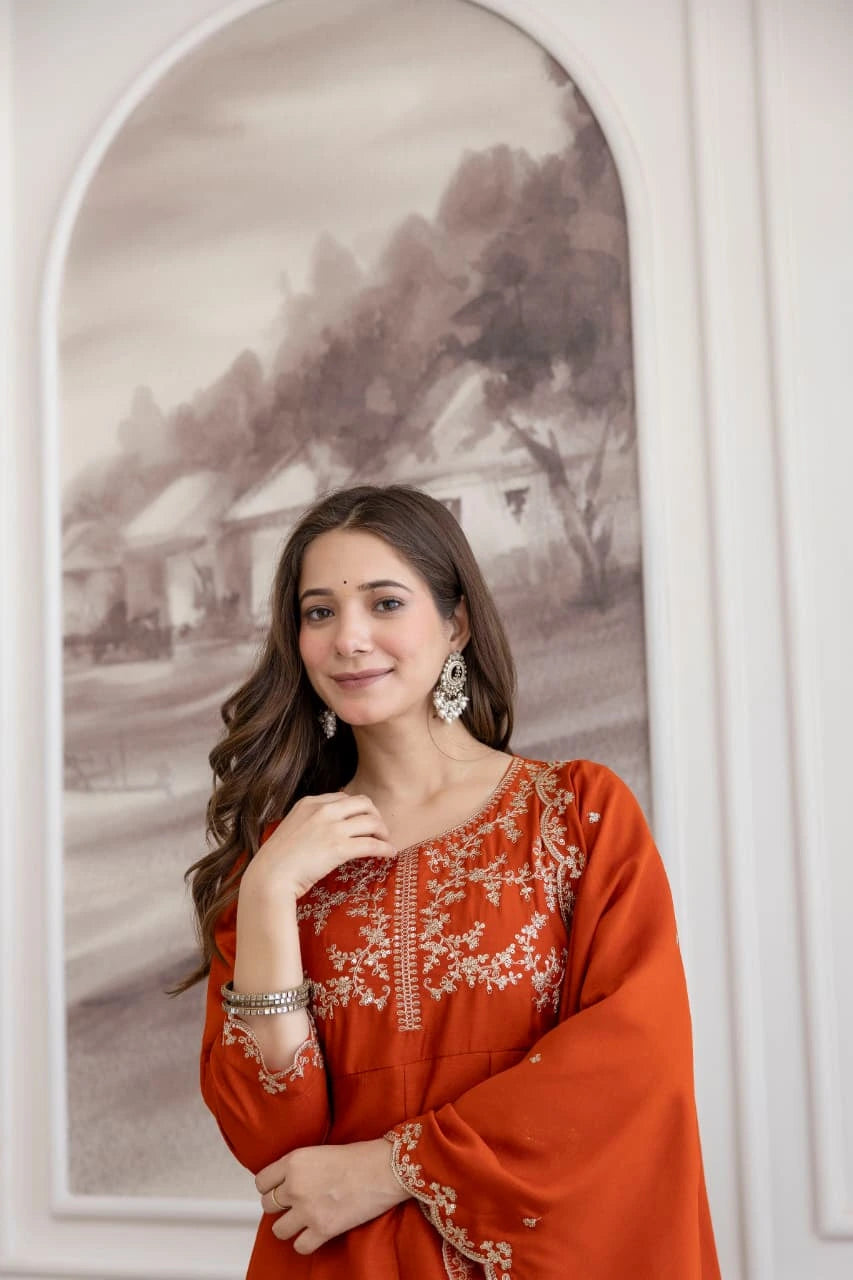 Woman in an orange traditional outfit standing in front of a framed painting