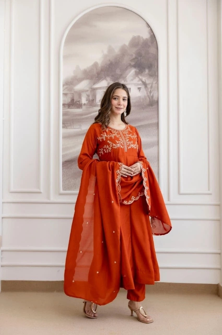 Woman in a red traditional outfit standing in a room with white walls and a decorative mirror.