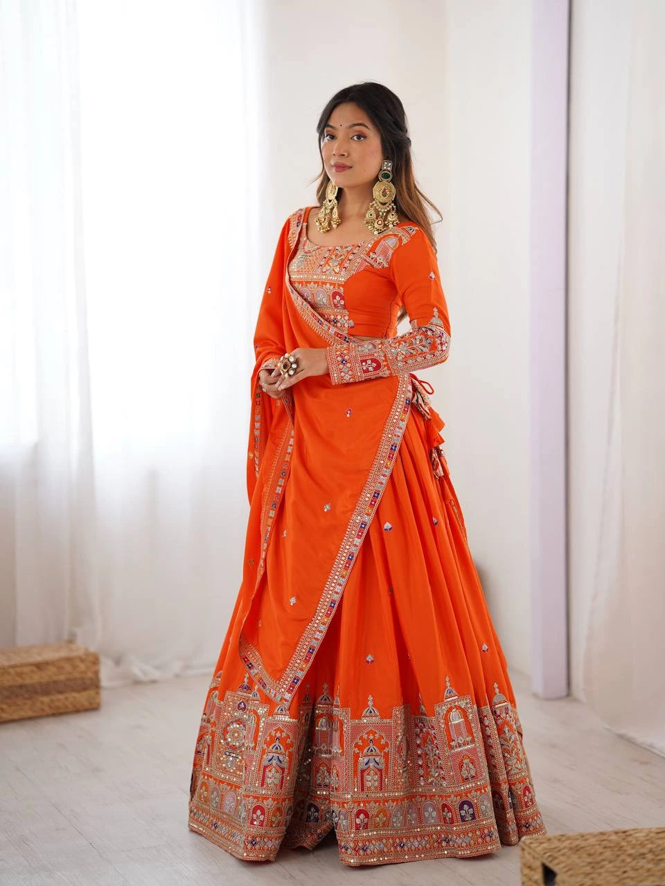 Woman wearing an orange embroidered saree with a white background