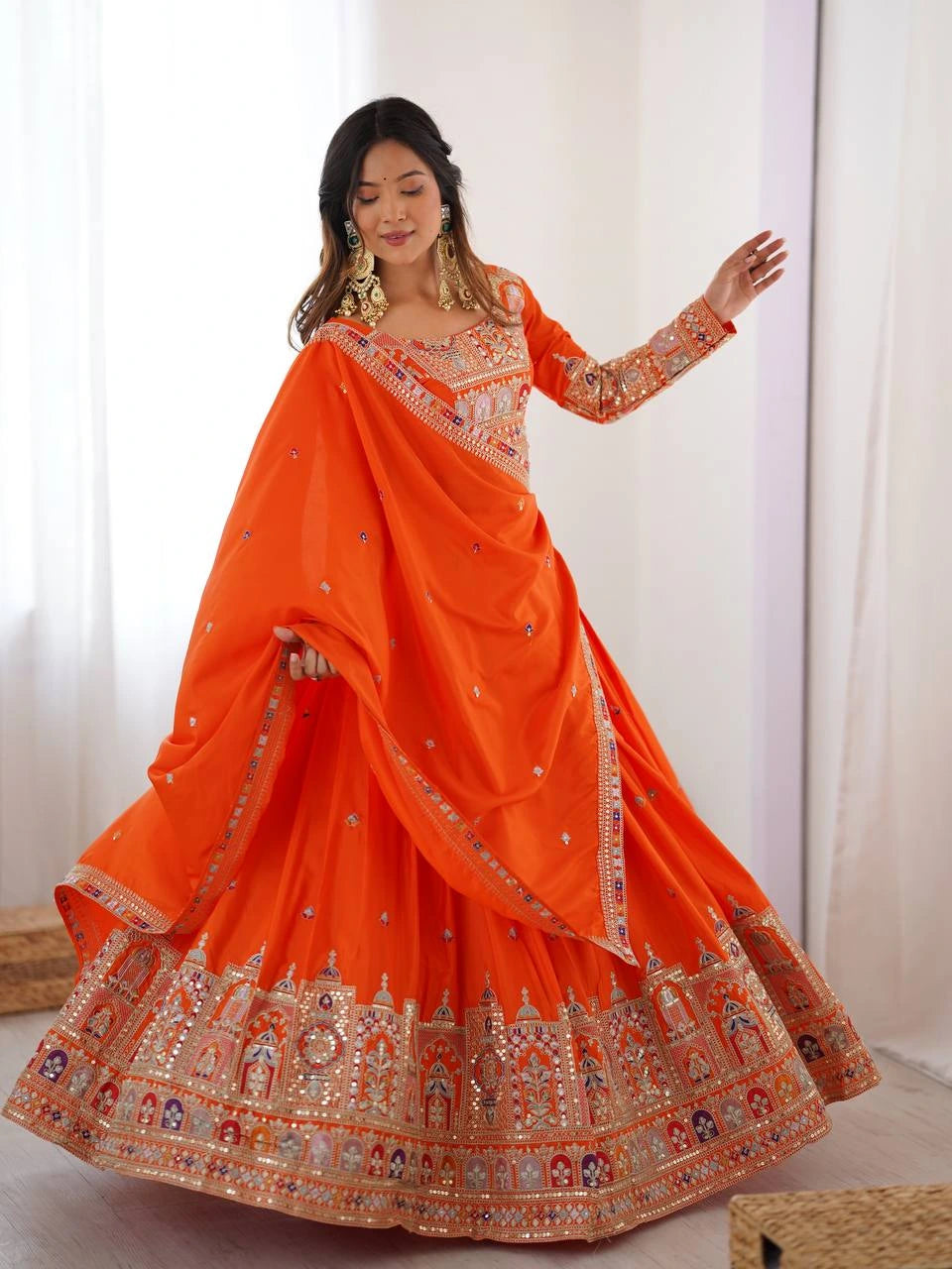 Woman wearing an orange embroidered saree with a white background