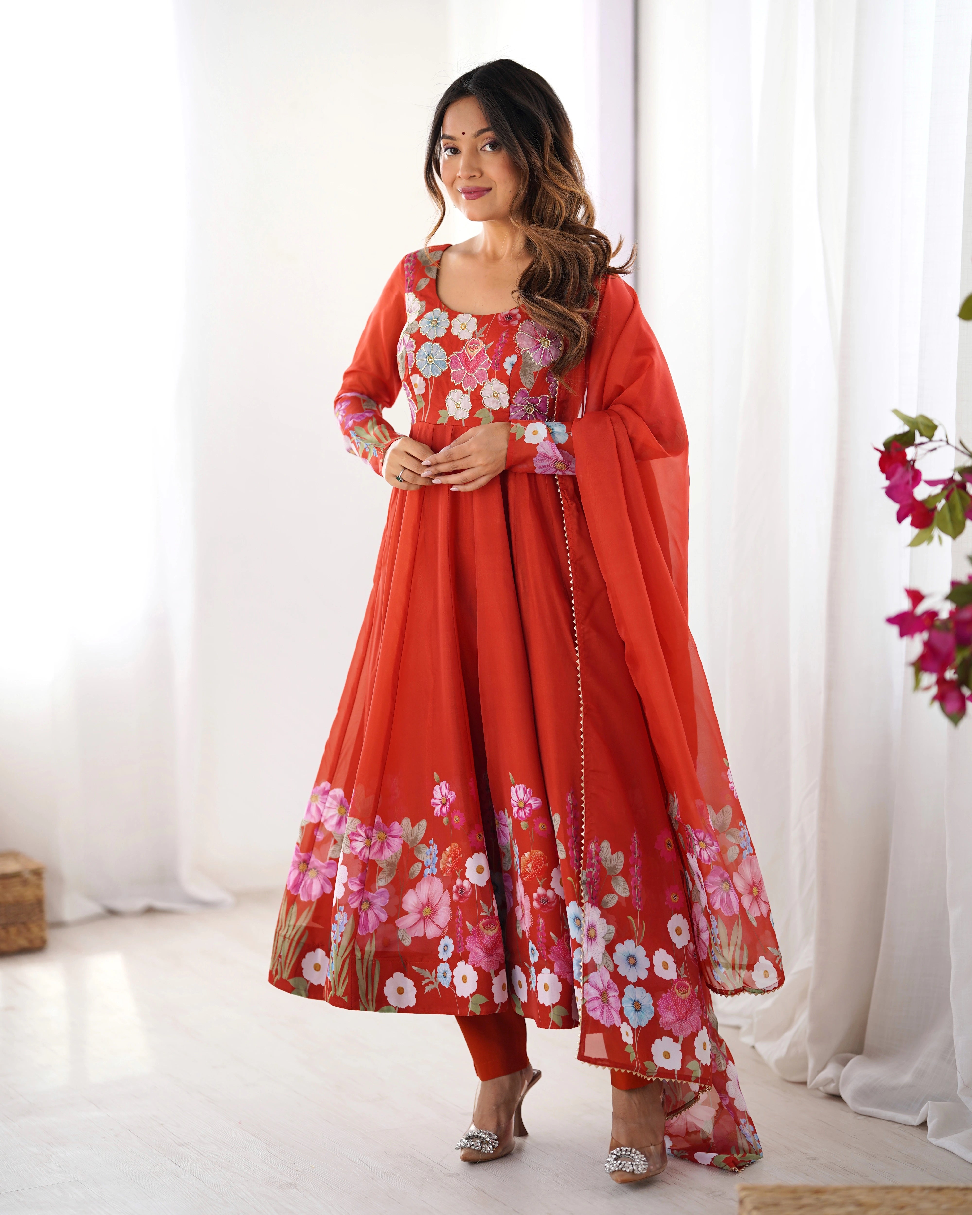Woman wearing a red floral traditional outfit with a white curtain background