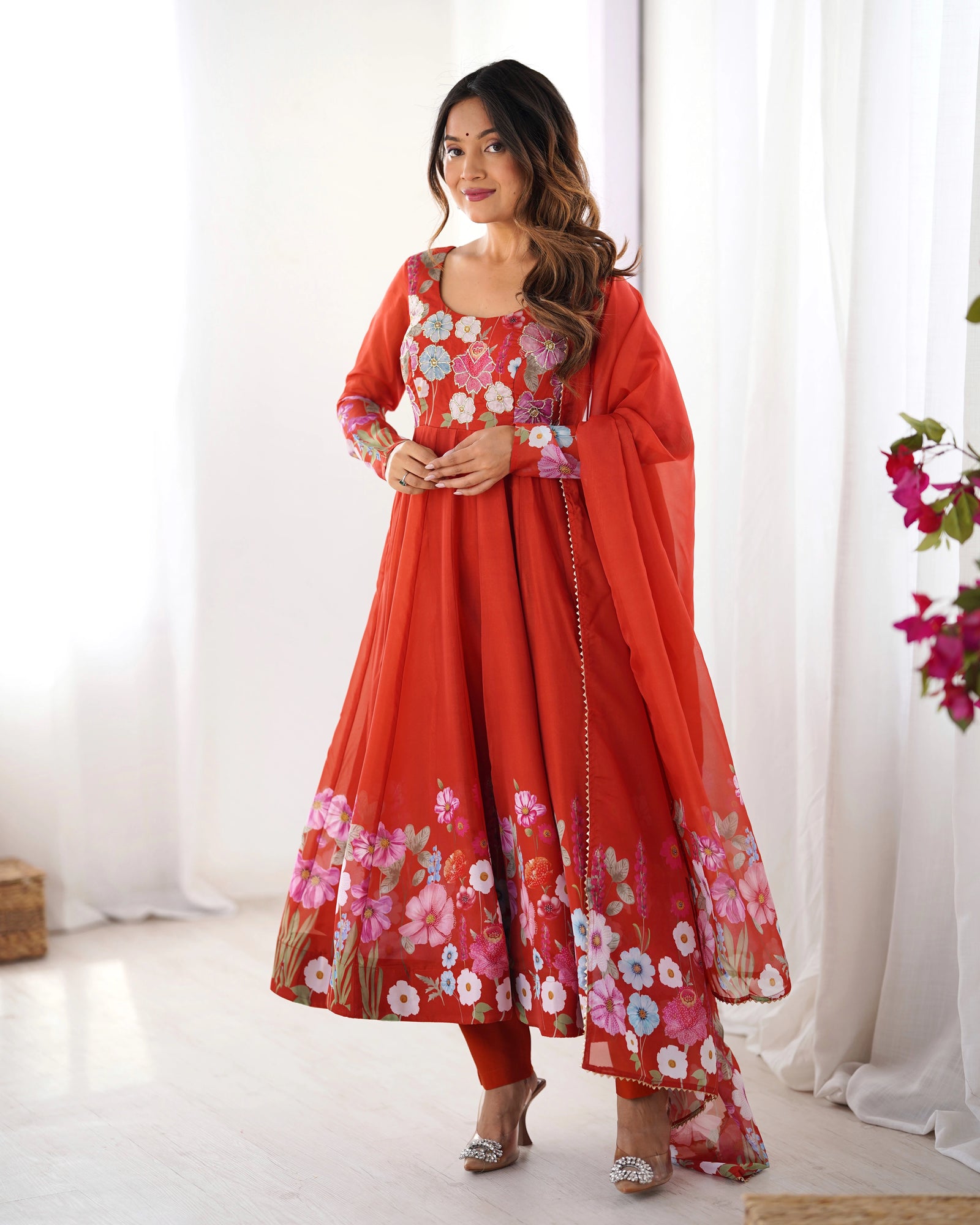 Woman wearing a red floral traditional outfit with a white curtain background
