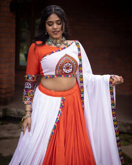 Woman wearing a traditional outfit with orange and white colors, decorated with colorful patterns.
