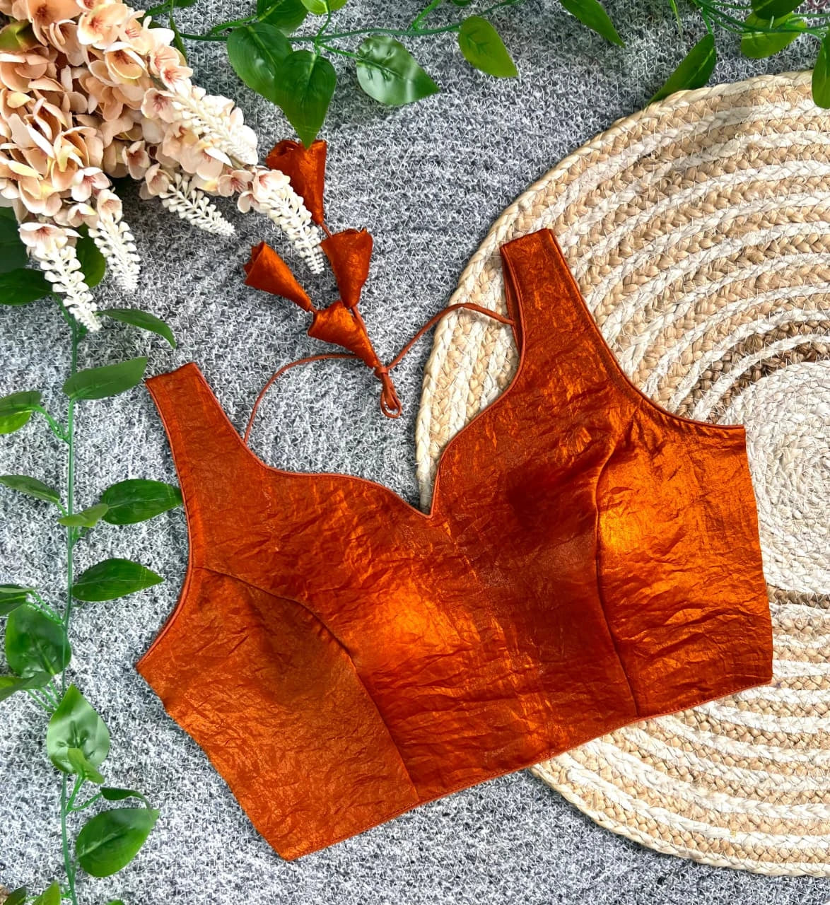 Orange textured top on a textured surface with floral and leaf decorations