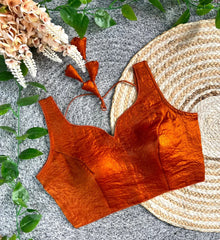 Orange textured top on a textured surface with floral and leaf decorations