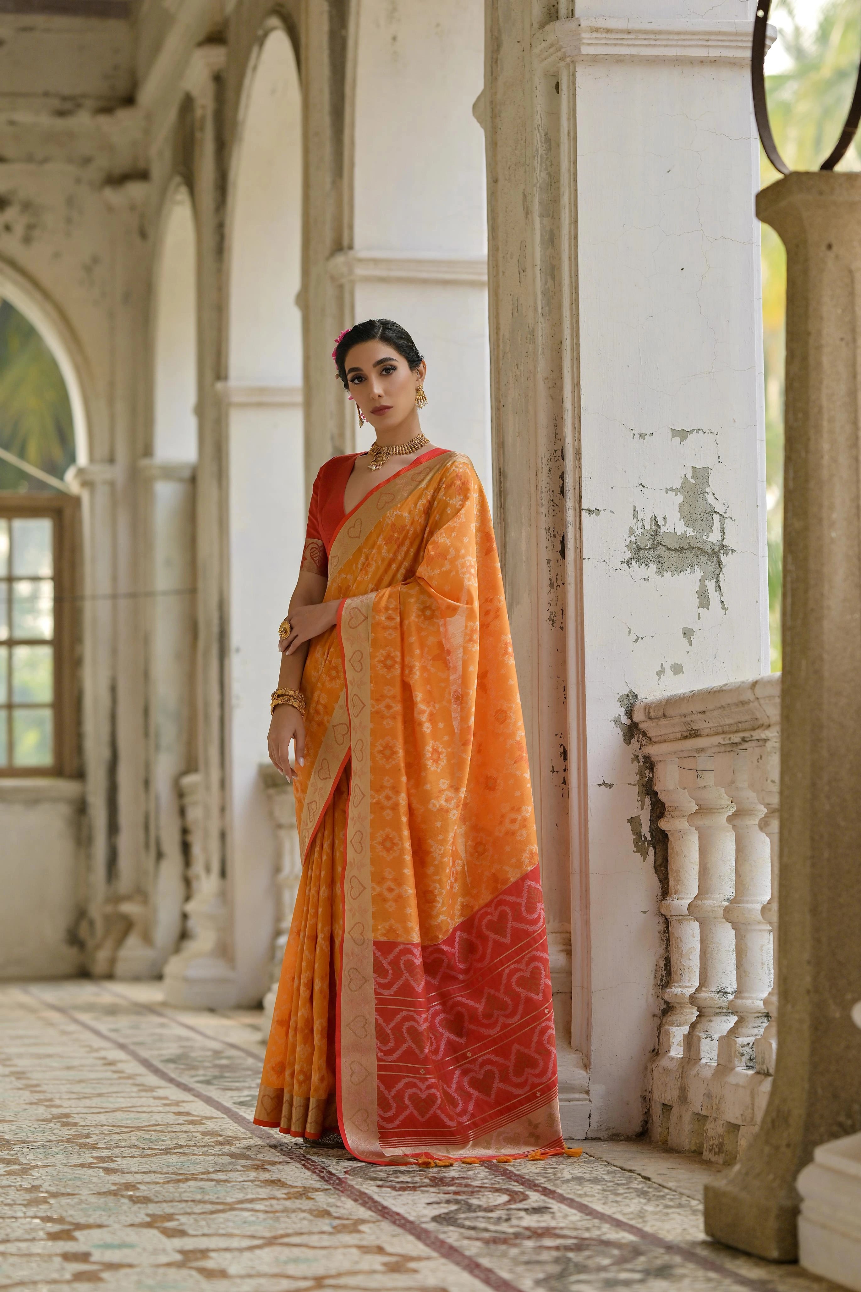 Woman in an orange saree standing in a decorative interior setting
