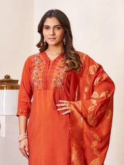 Woman wearing an orange embroidered traditional outfit against a neutral background