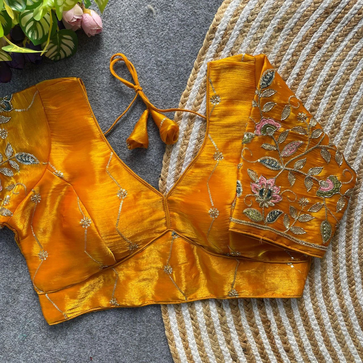 Yellow embroidered blouse on a textured surface with flowers in the background