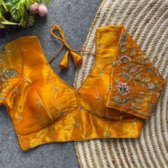 Yellow embroidered blouse on a textured surface with flowers in the background