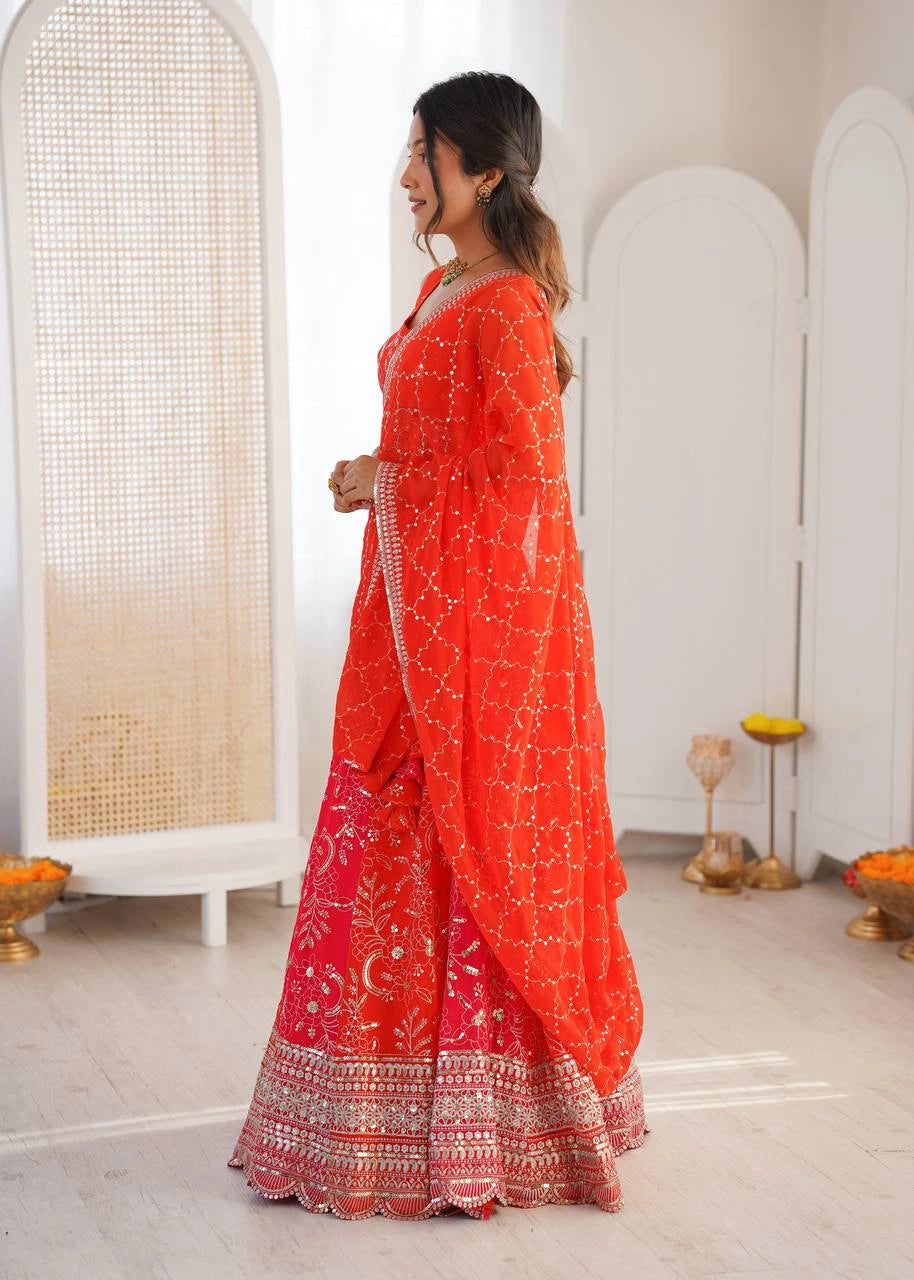 Woman in a red saree with white patterns standing in a room with white walls and minimal decor.