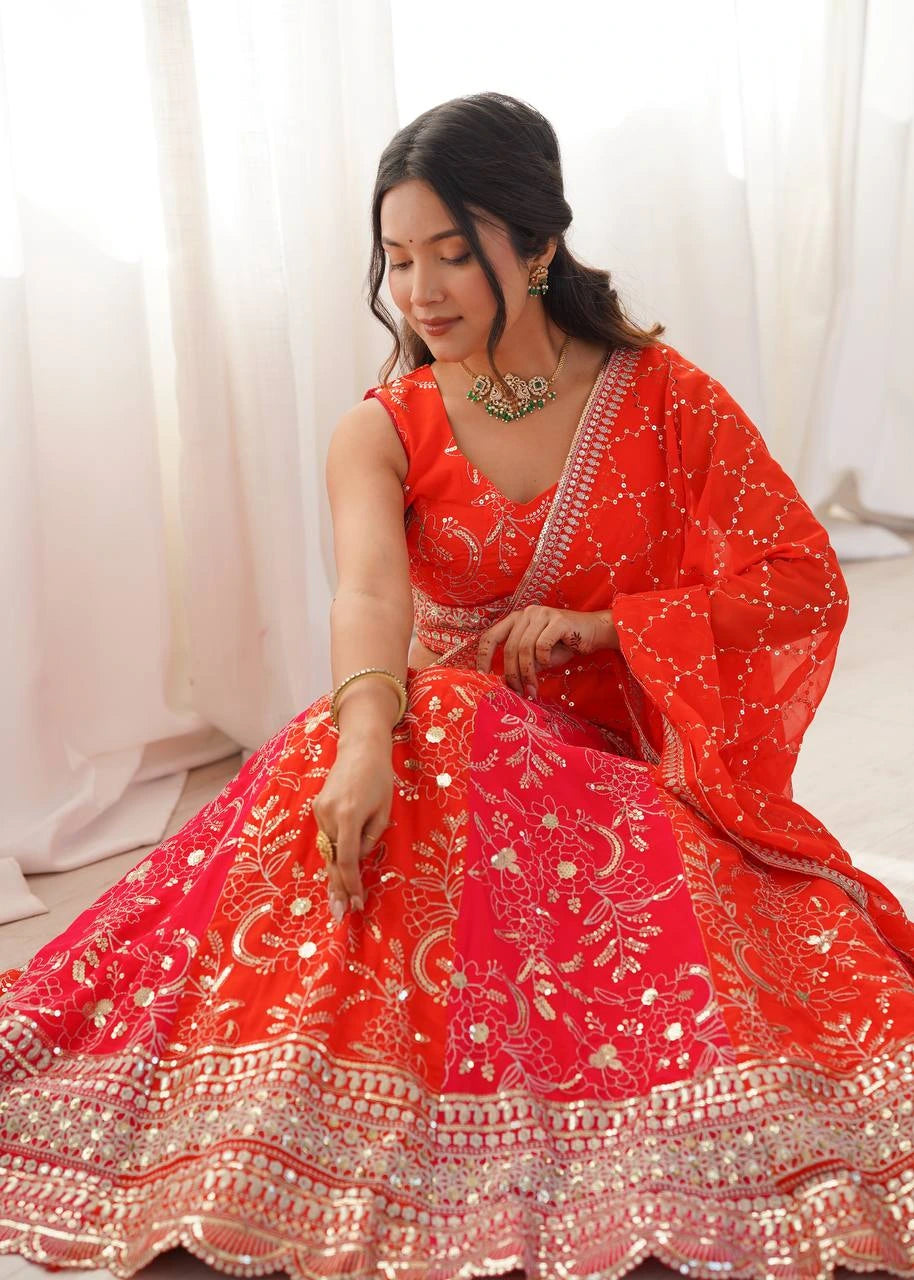 Woman in a red traditional outfit with gold embroidery sitting against a white curtain.
