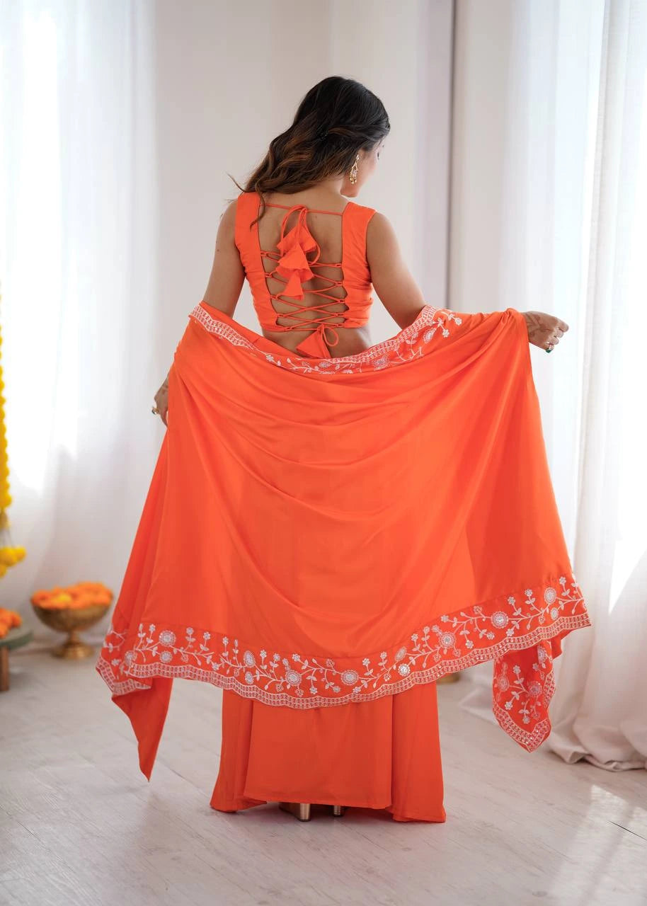 Woman wearing an orange traditional outfit with a sheer dupatta in a bright room.
