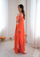 Woman wearing an orange saree with a white blouse in a bright room.