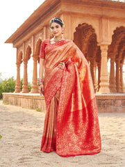 Woman in a red saree standing in front of an architectural structure.
