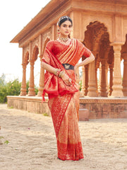 Woman in a red saree standing in front of an architectural structure.