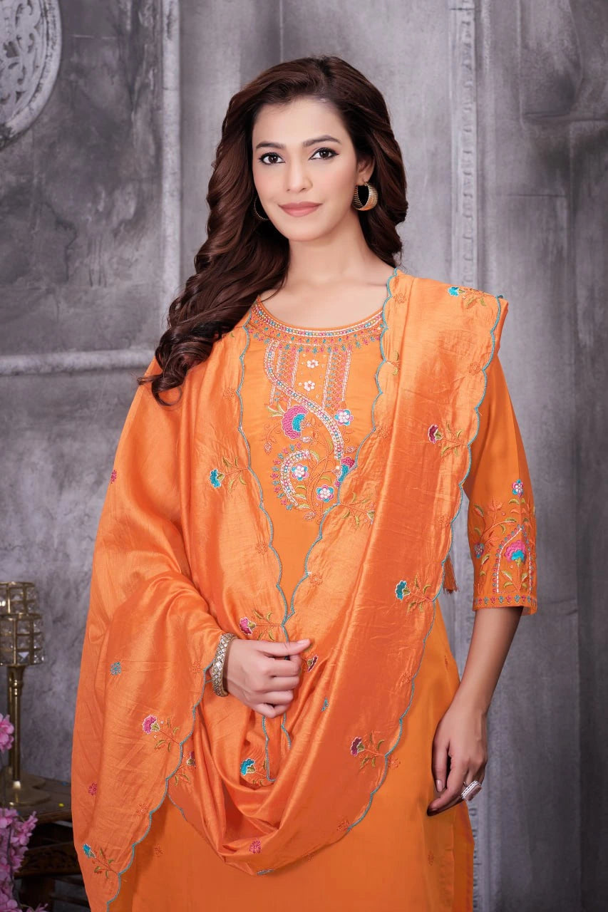 Woman wearing an orange embroidered traditional outfit against a gray background
