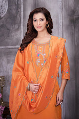 Woman wearing an orange embroidered traditional outfit against a gray background