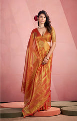 Woman wearing a traditional orange saree with a pink background