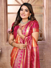 Woman wearing a traditional pink and orange saree with jewelry against a decorative wall.