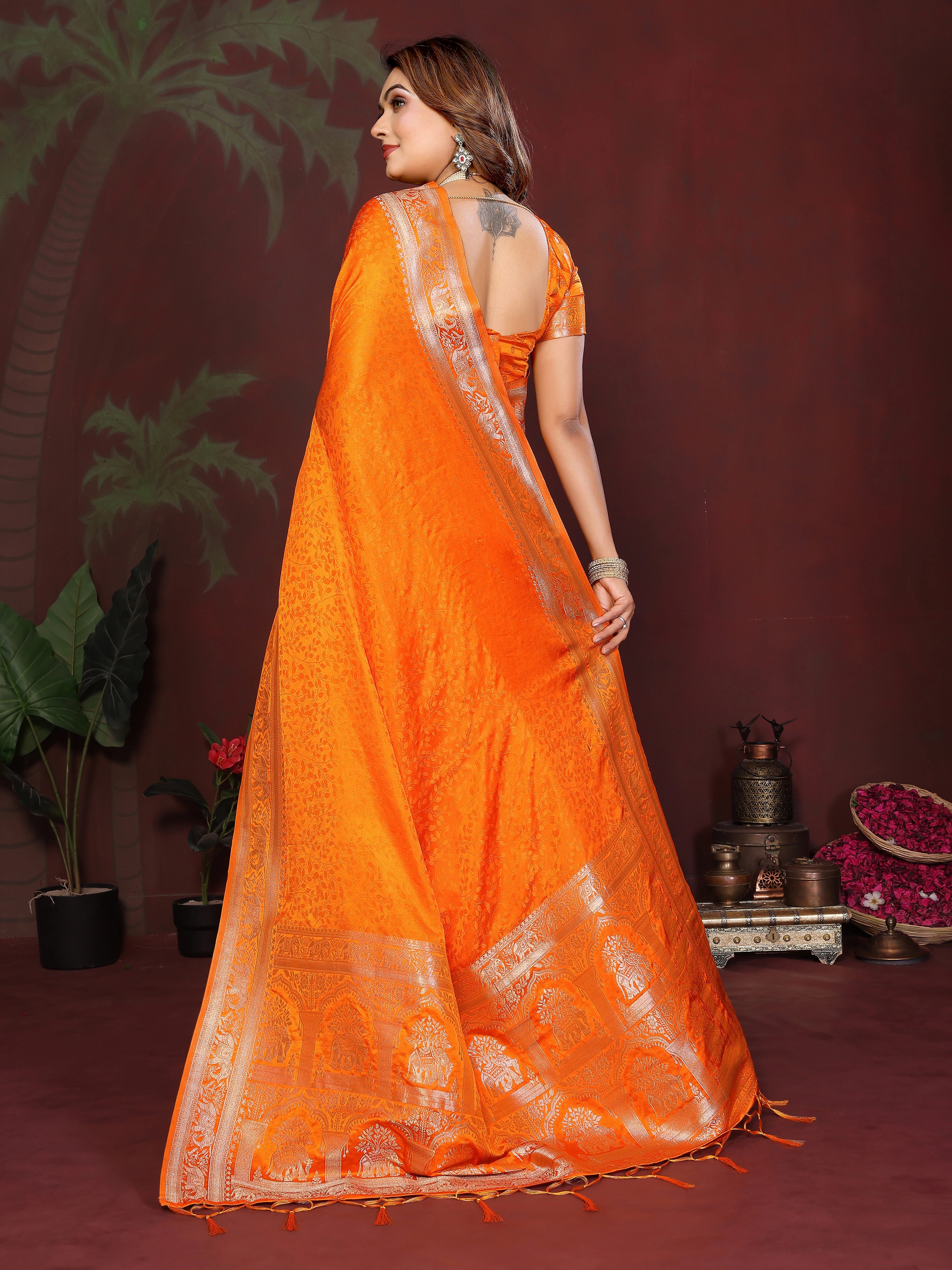 Woman wearing an orange saree with a white border against a dark background