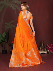 Woman wearing an orange saree with a white border against a dark background
