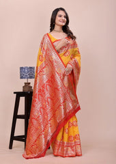 Woman wearing a yellow and orange saree with a lamp and stool in the background
