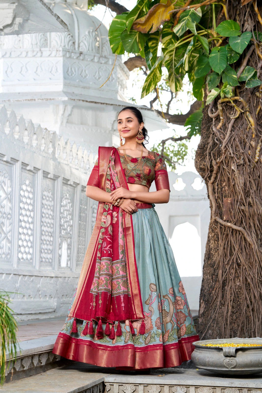 Traditional ethnic lehenga featuring a light blue skirt, maroon silk border, floral artwork, and tassel detailed dupatta.