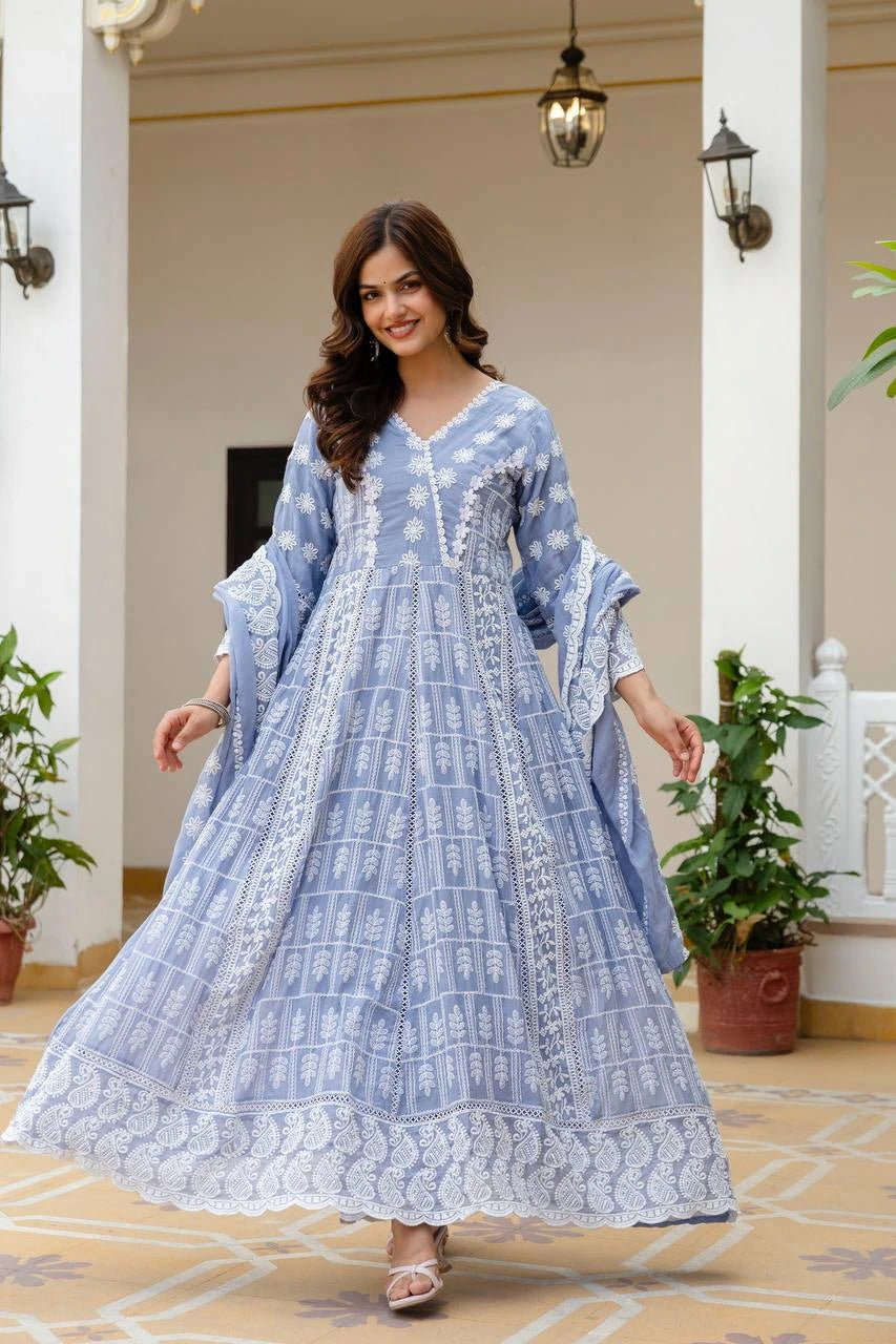 Woman in a blue and white patterned dress standing in an elegant indoor setting.