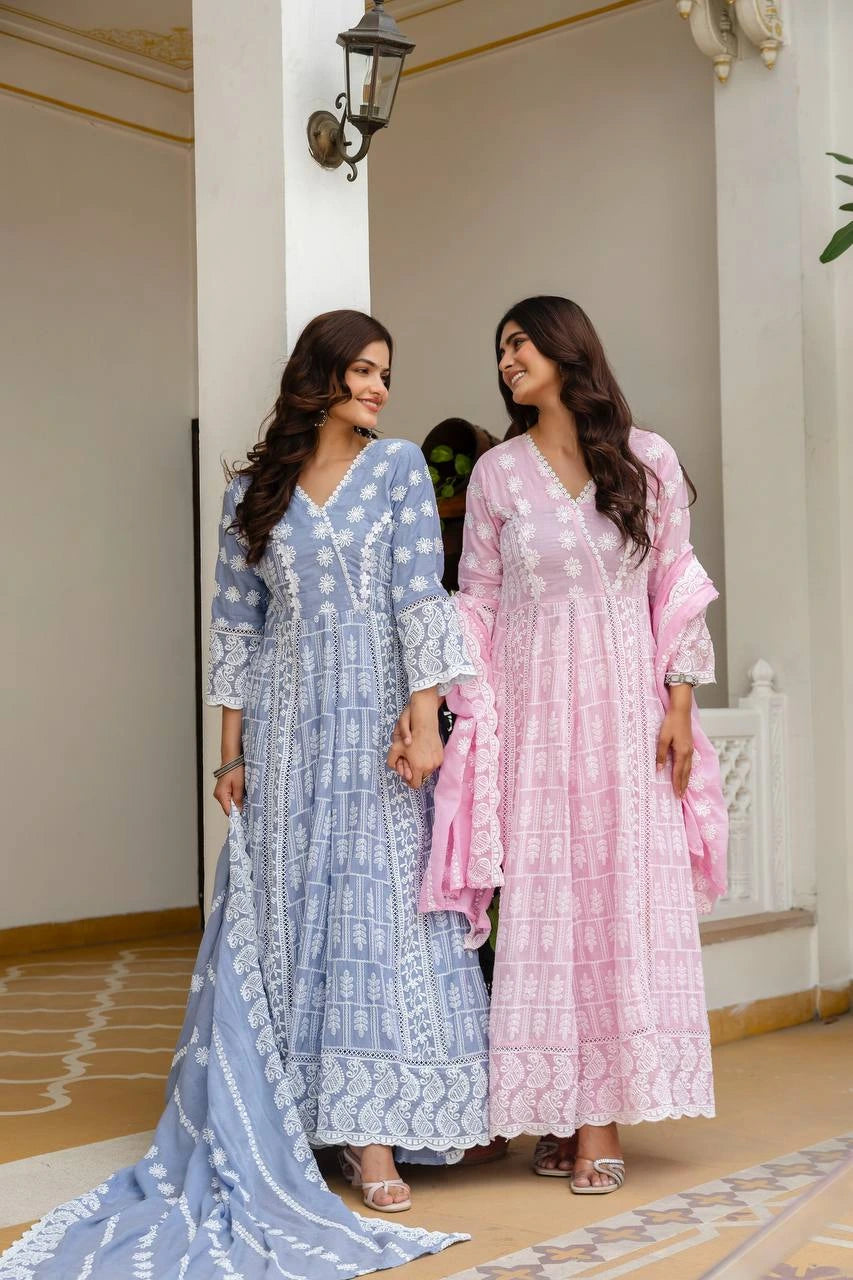 Two women in traditional outfits standing in a decorative indoor setting.