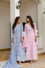 Two women in traditional outfits standing in a decorative indoor setting.