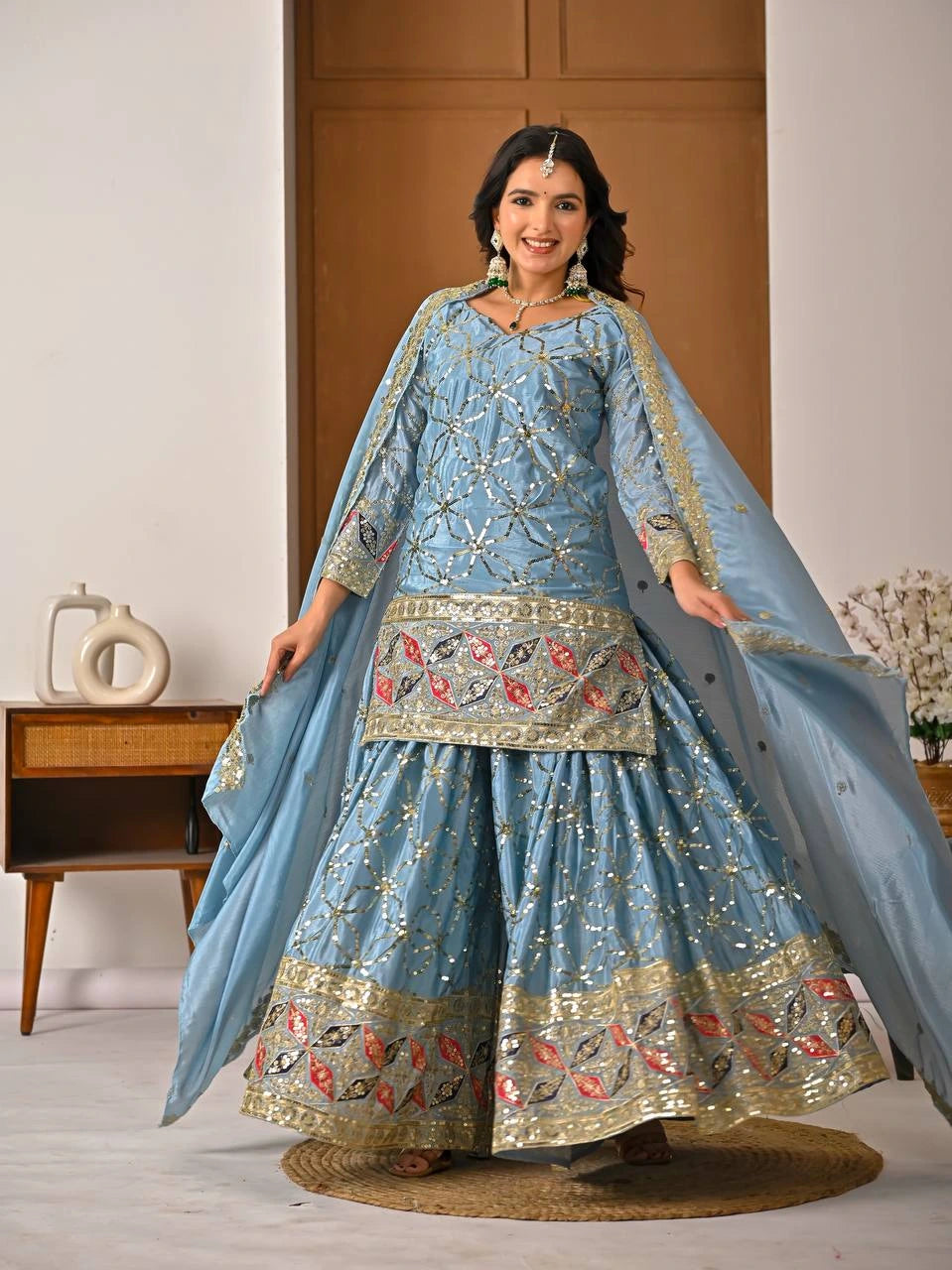 Woman in a light blue embroidered traditional outfit with a matching dupatta.