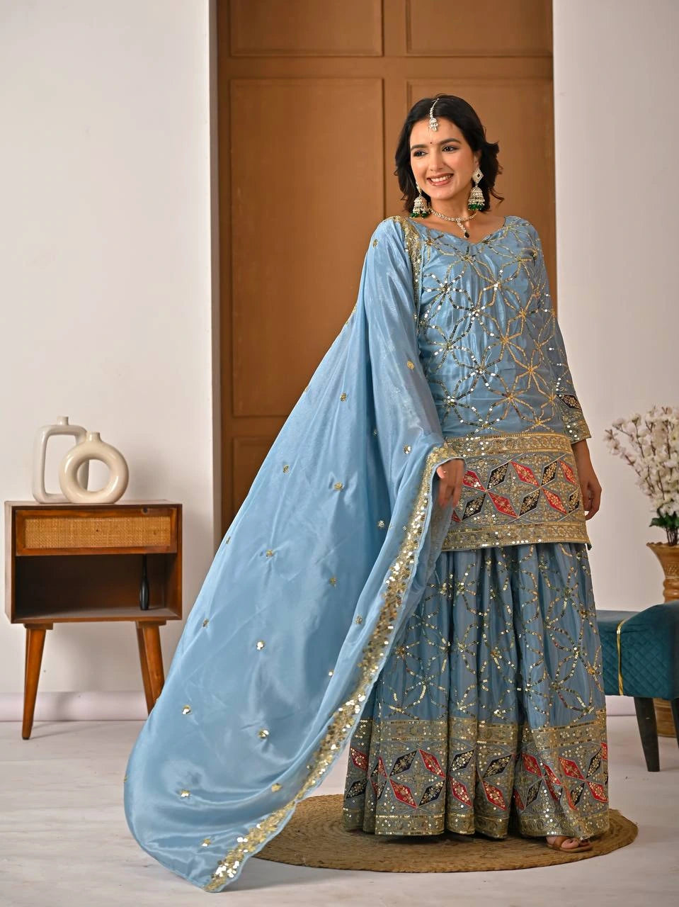 Woman in a traditional outfit with a blue dupatta in an indoor setting