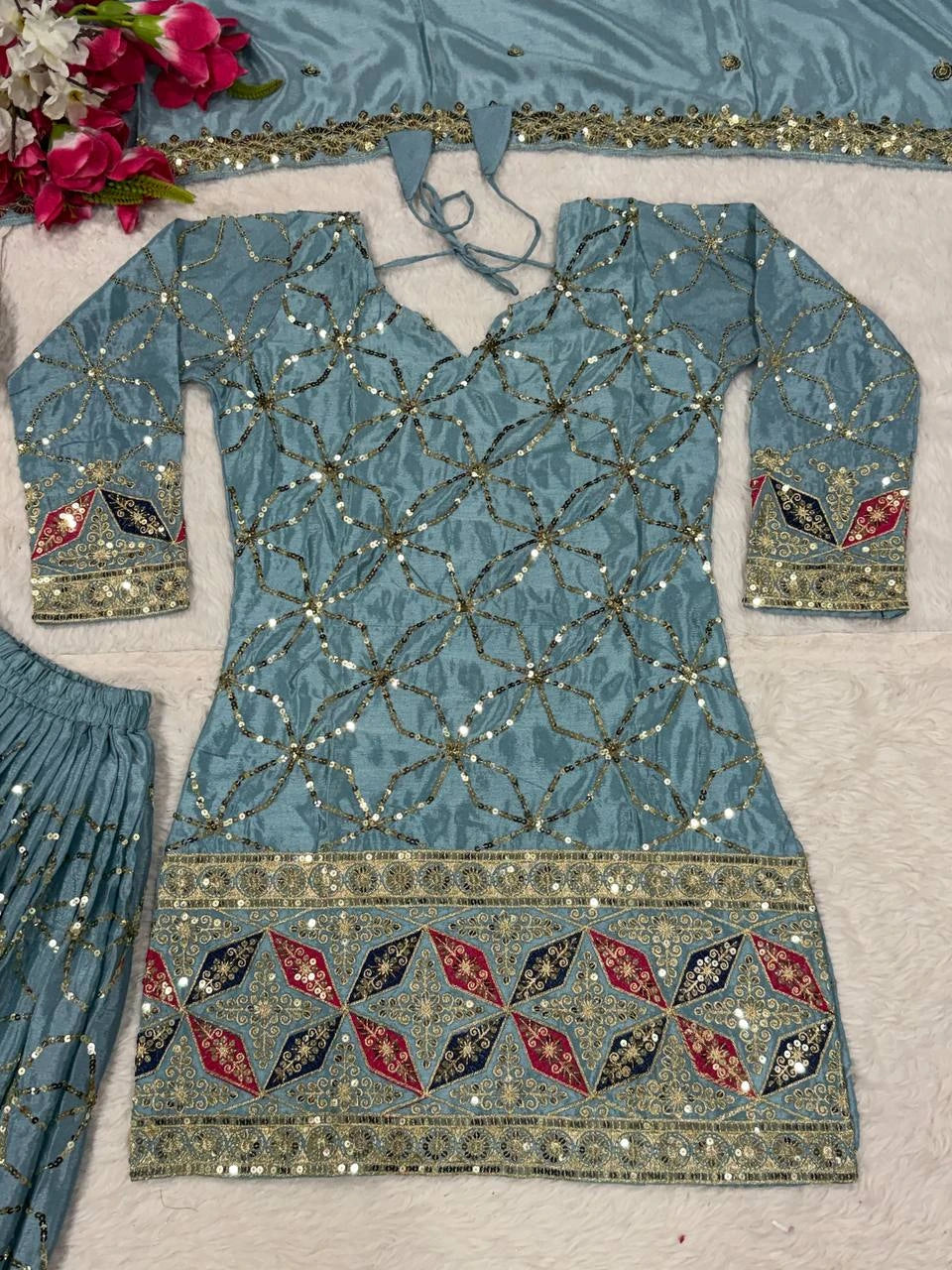 Decorative blue garment with intricate patterns on a light gray background