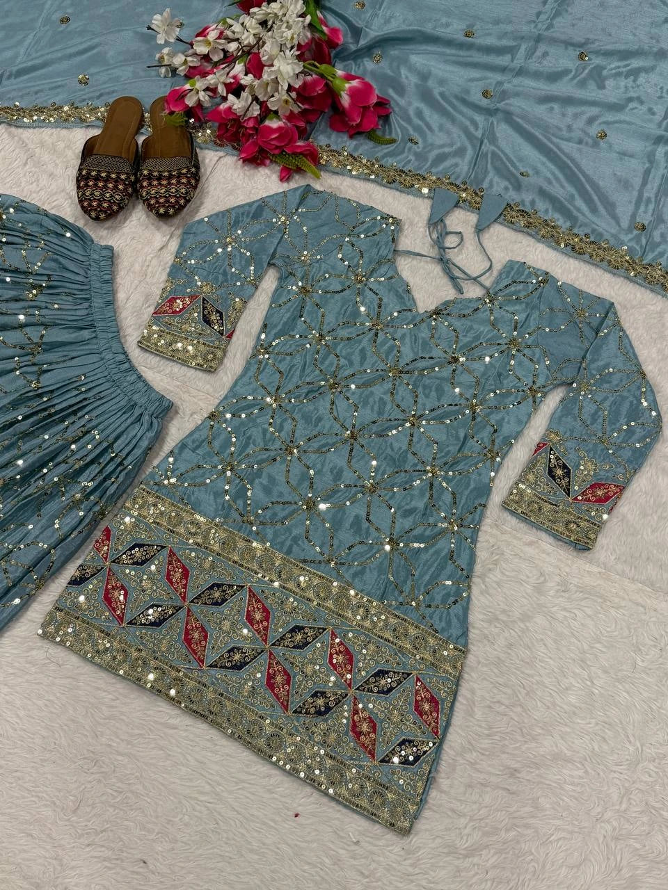 Blue embroidered traditional outfit with floral decorations on a textured surface