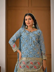 Woman wearing a traditional embroidered outfit with jewelry against a neutral background