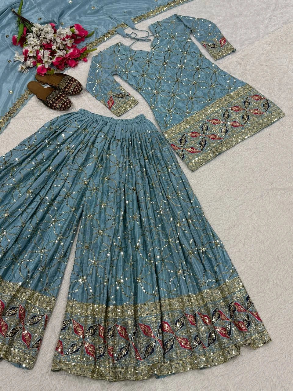 Traditional blue embroidered outfit with floral decorations on a light gray background