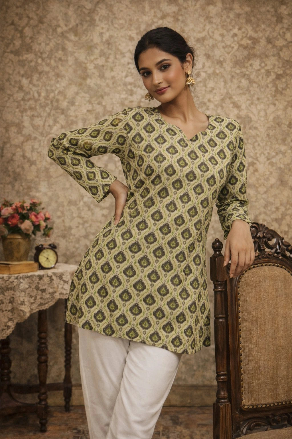 Woman wearing a green patterned kurta with white pants in a vintage room setting.