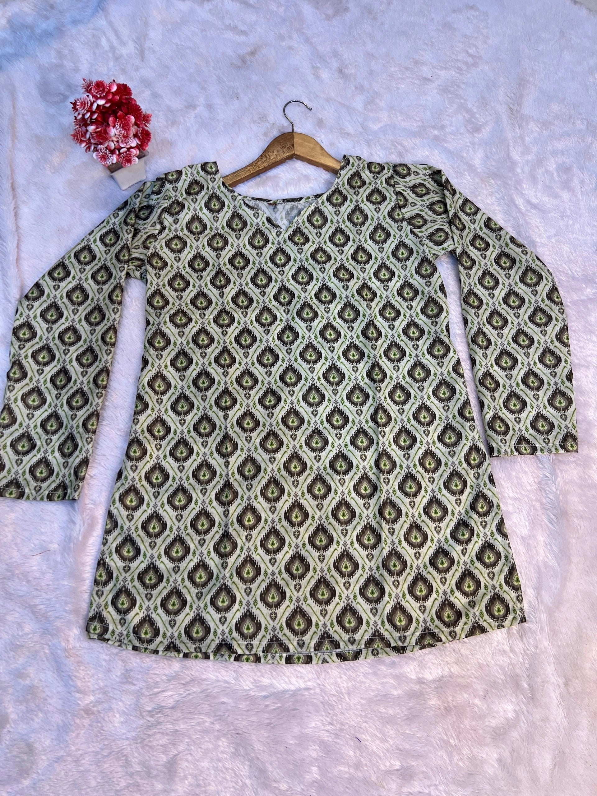 Green patterned shirt on a hanger against a light gray background