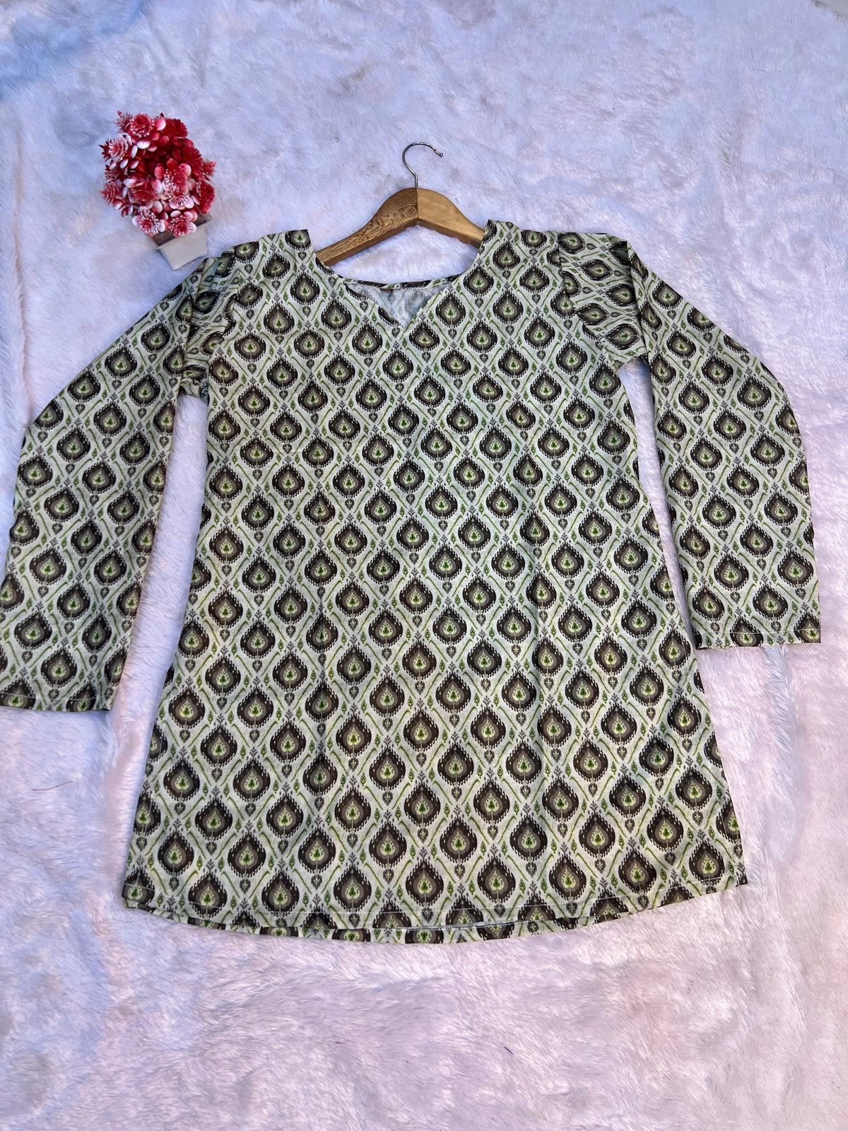 Green patterned shirt on a hanger against a light gray background