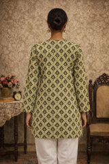 Person wearing a green patterned kurta with white pants in a room setting.