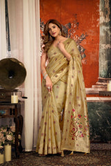 Woman in a light green saree with floral patterns standing in a room with vintage decor.