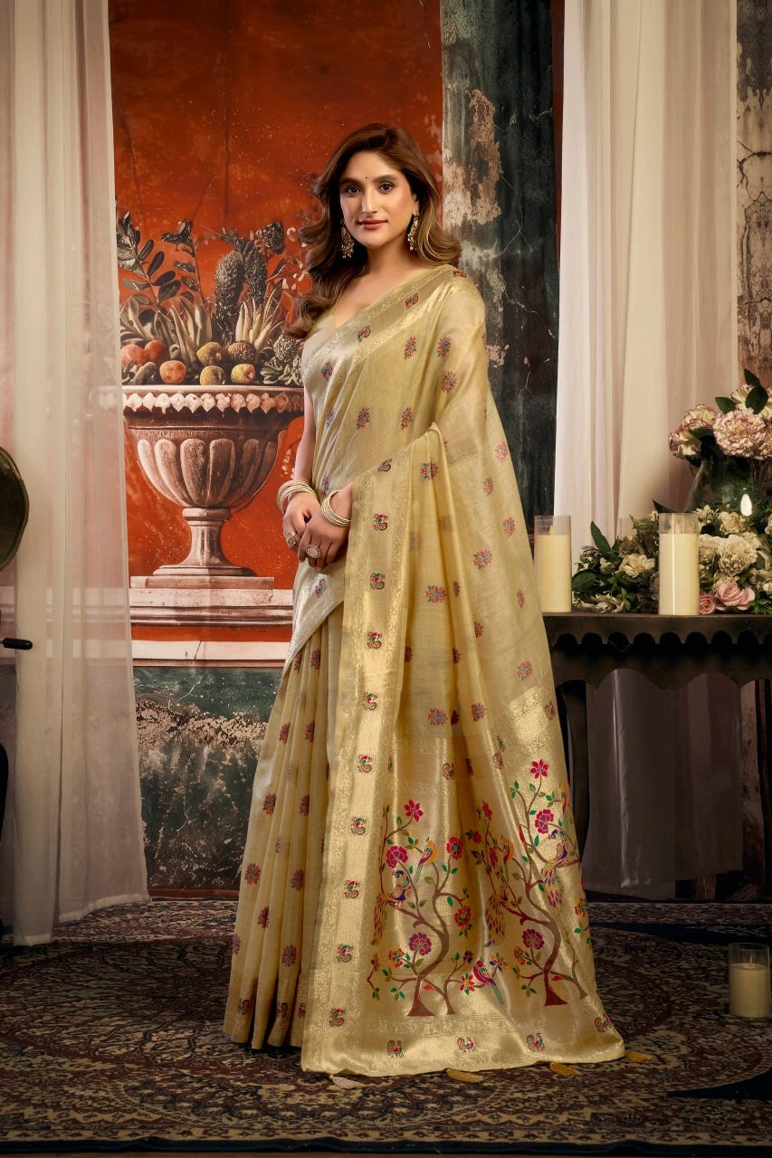 Woman in a light-colored saree with floral patterns in an elegant indoor setting.