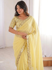 Woman wearing a yellow saree with gold embroidery indoors.