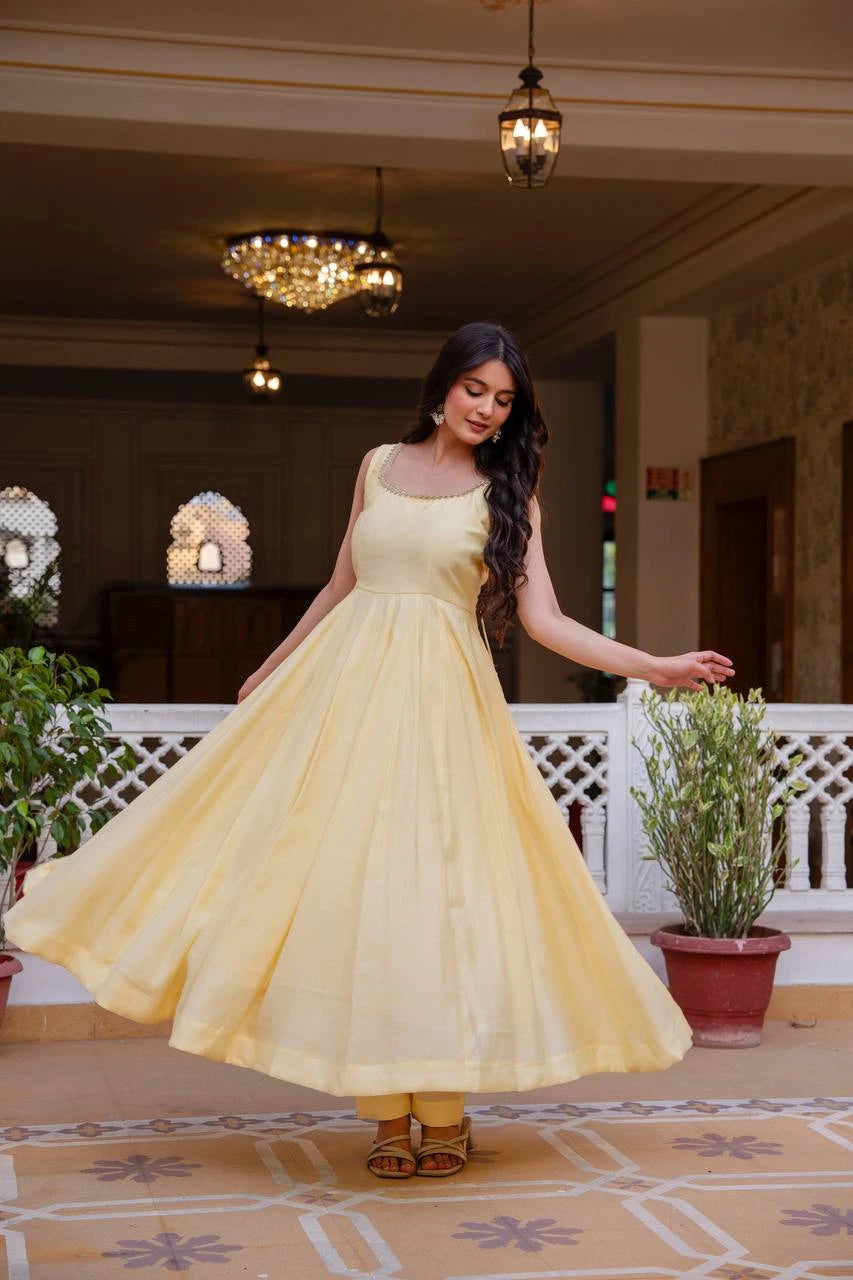 Woman in a yellow dress standing in an elegant indoor setting with decorative elements.