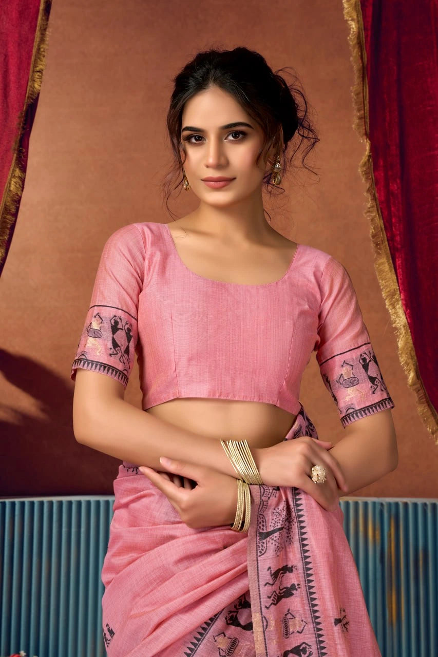 Woman wearing a pink saree with a traditional design against a brown and red background