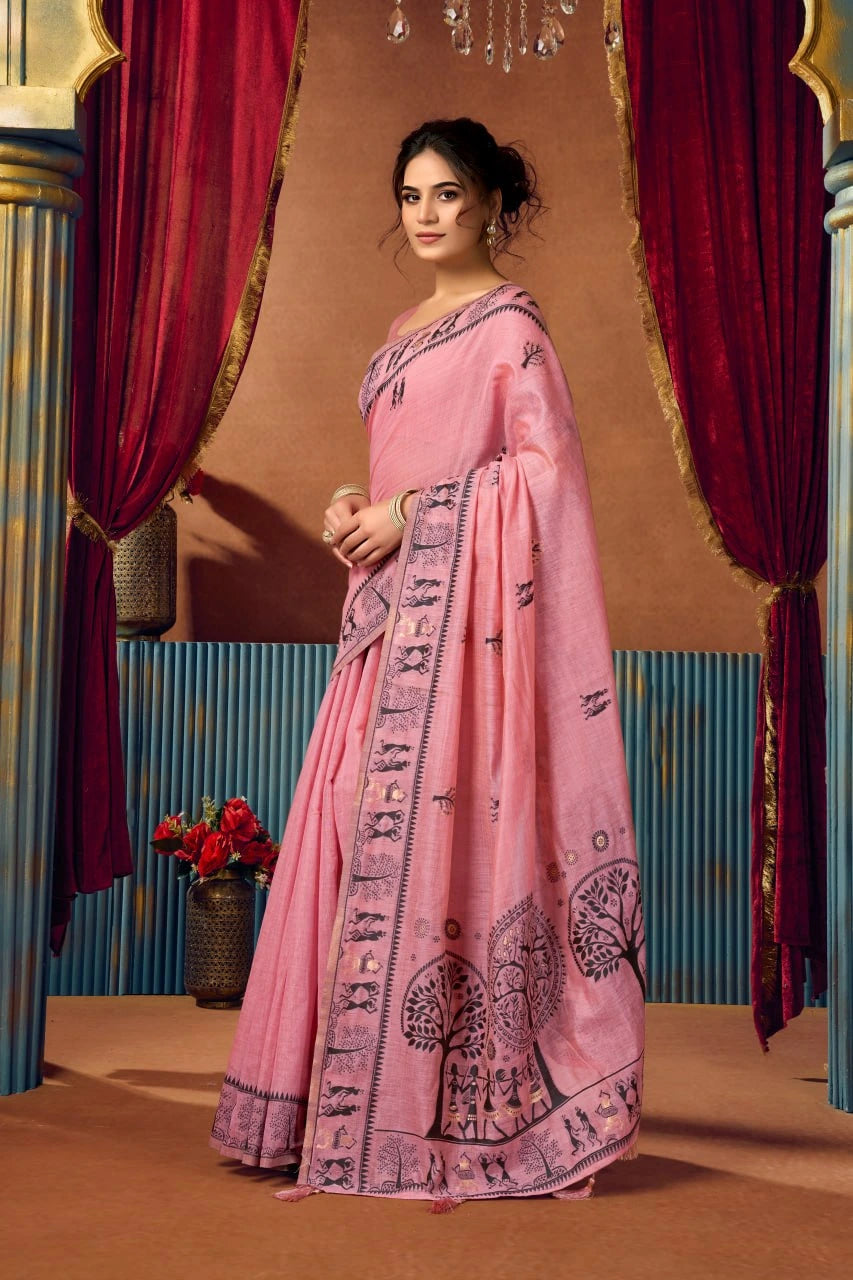 Woman in a pink traditional outfit with intricate patterns standing in front of decorative curtains.