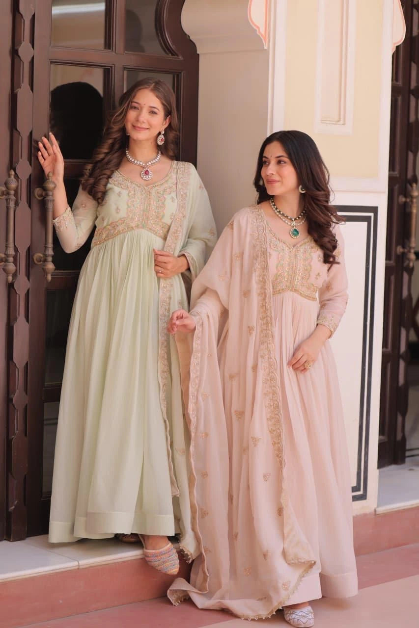 Two women in traditional outfits standing in front of a decorative door.