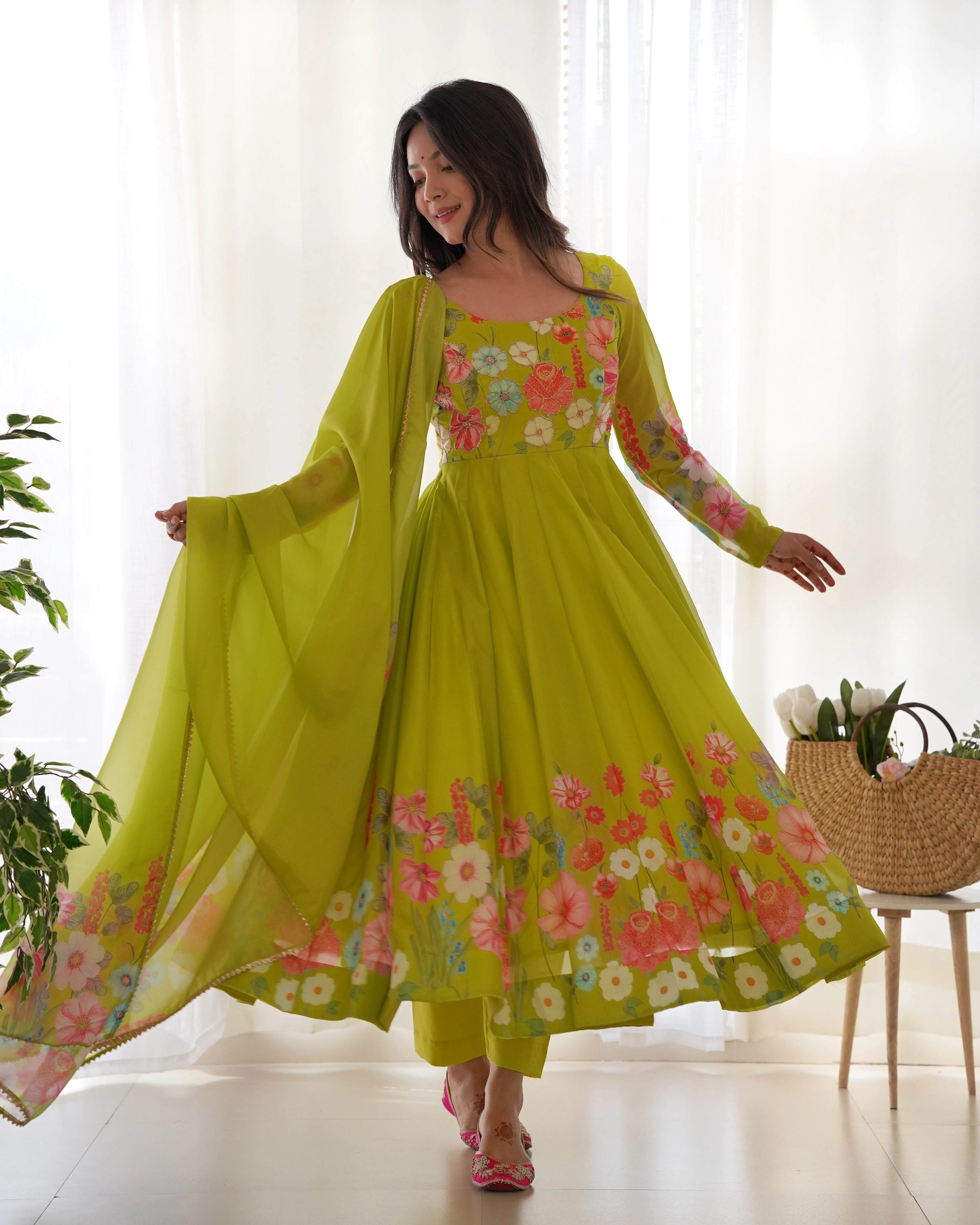 Woman wearing a bright green floral dress with a sheer dupatta in a bright room.