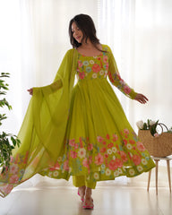 Woman wearing a bright green floral dress with a sheer dupatta in a bright room.